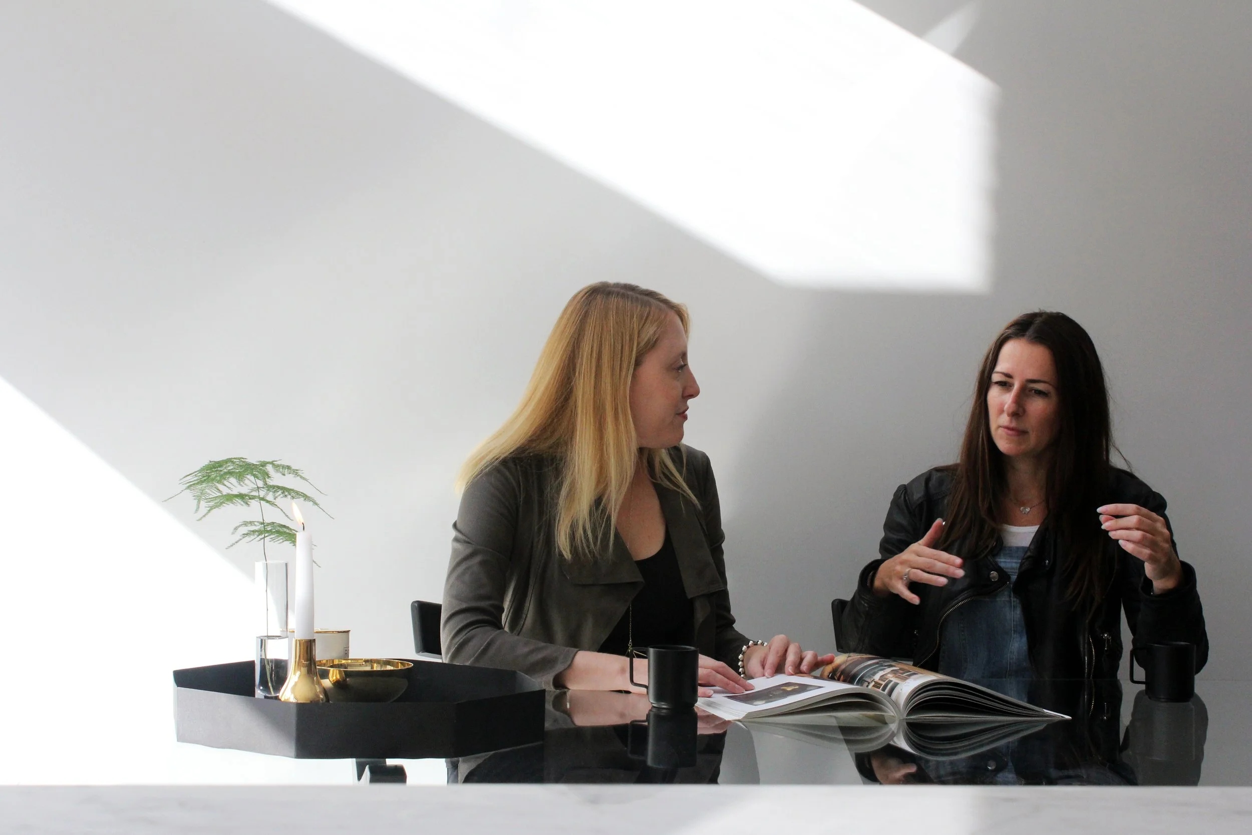 Two women in conversation at a table in a bright modern interior in London