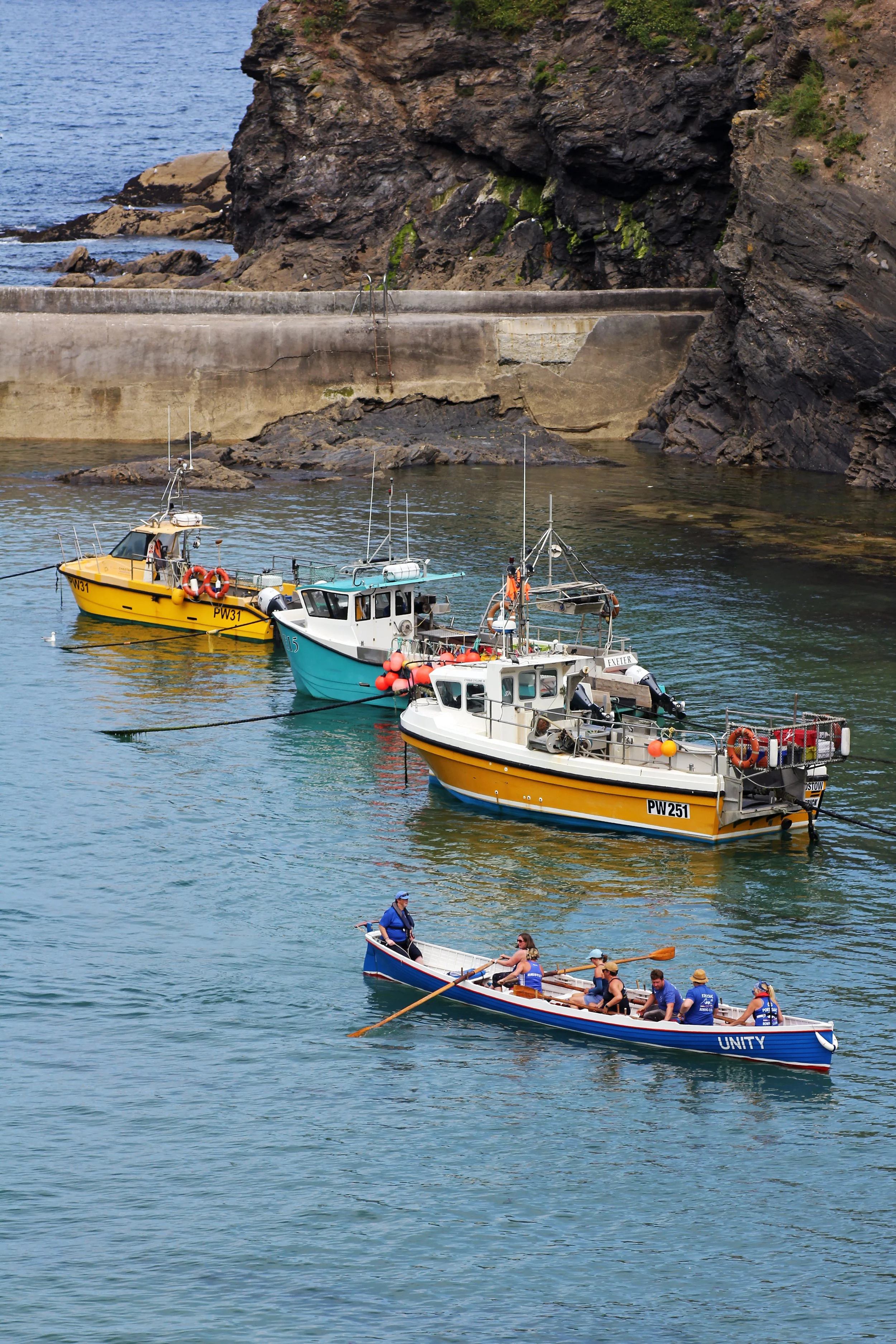 Colourful fishing boats moored in the Port Isaac sheltered rocky harbour, Cornwall