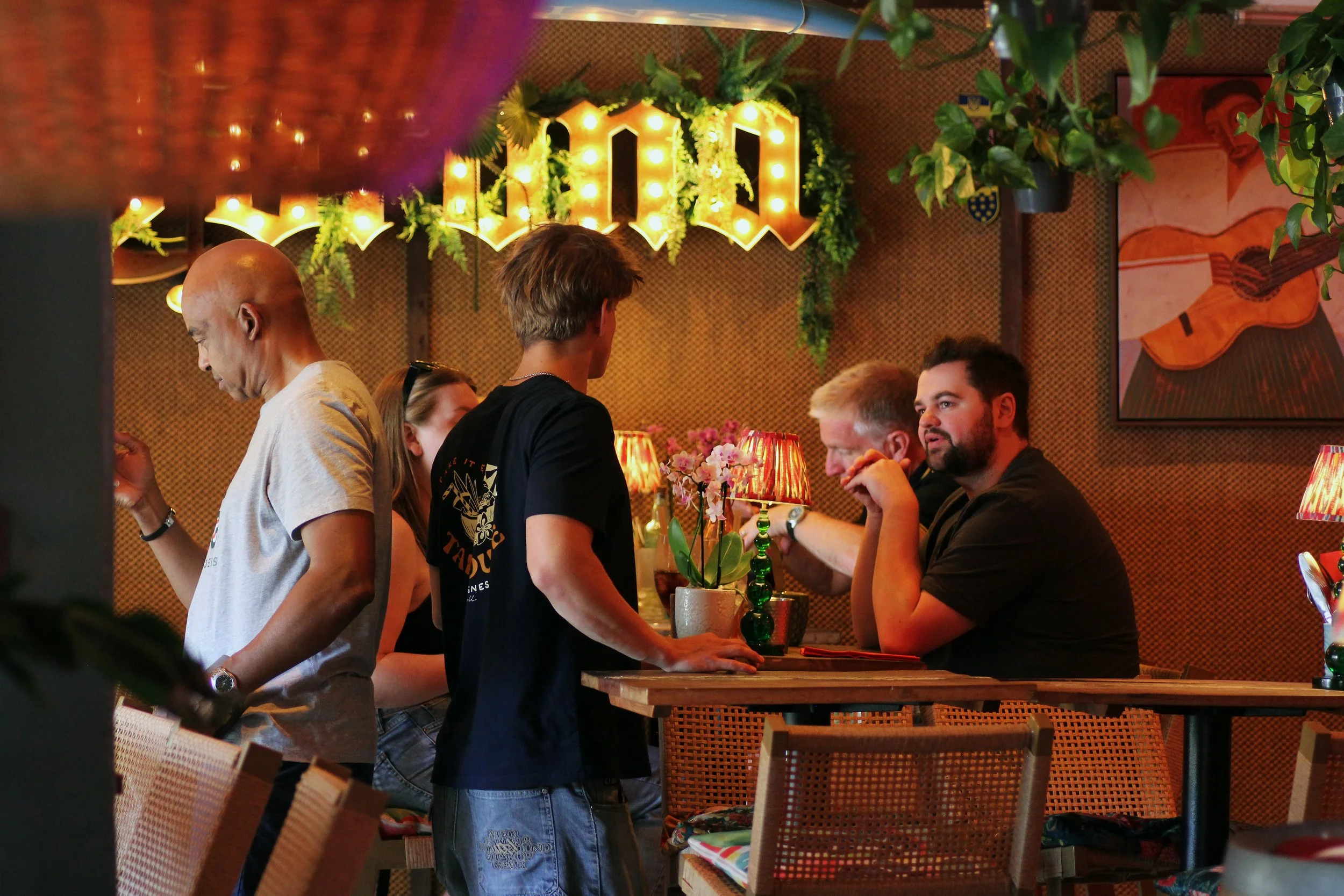 Customers talking inside colourful, warmly lit taphouse bar in St. Agnes, Cornwall