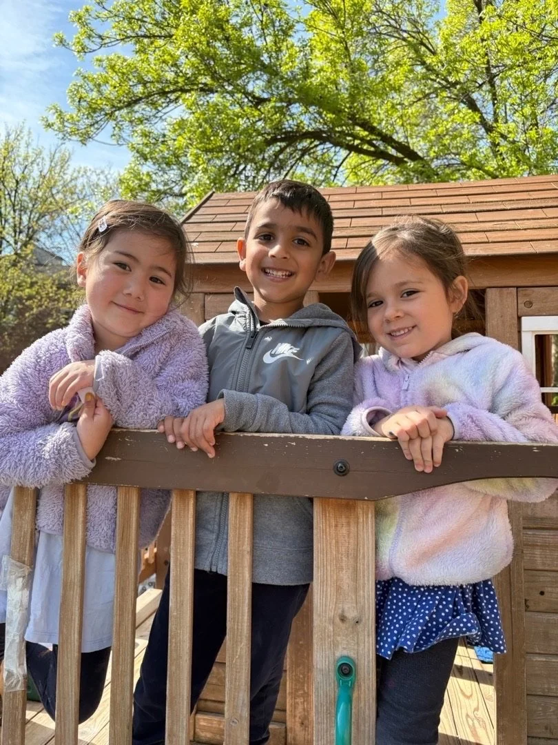 Three kids posing for a photo on a treehouse.
