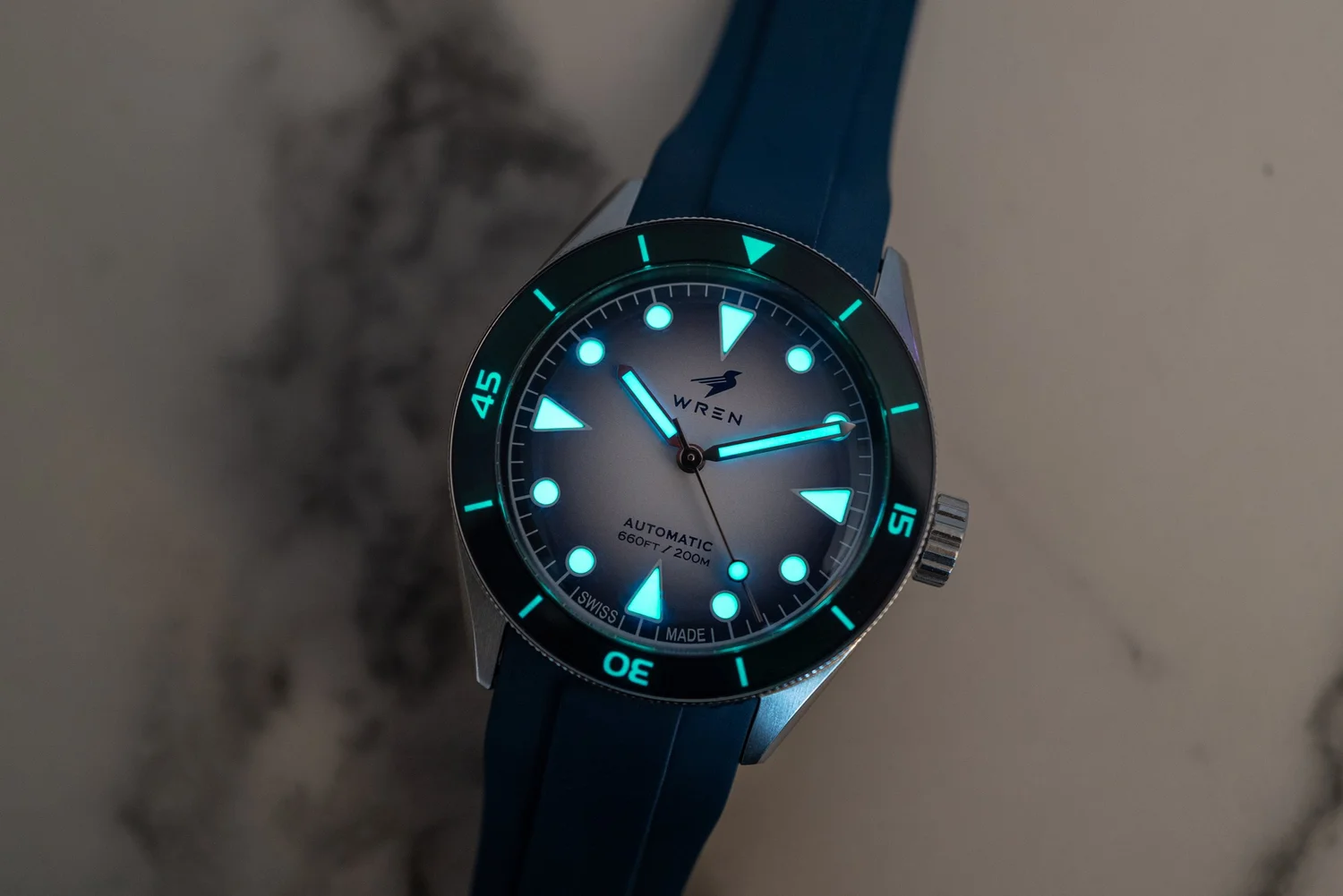 Wren dive watch lume glowing in low light on a rubber strap