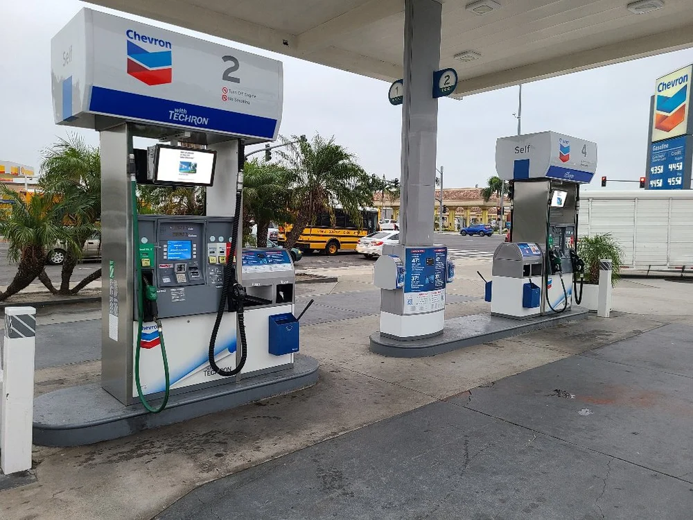 Gas pump with a built-in digital ad screen on a sunny station forecourt