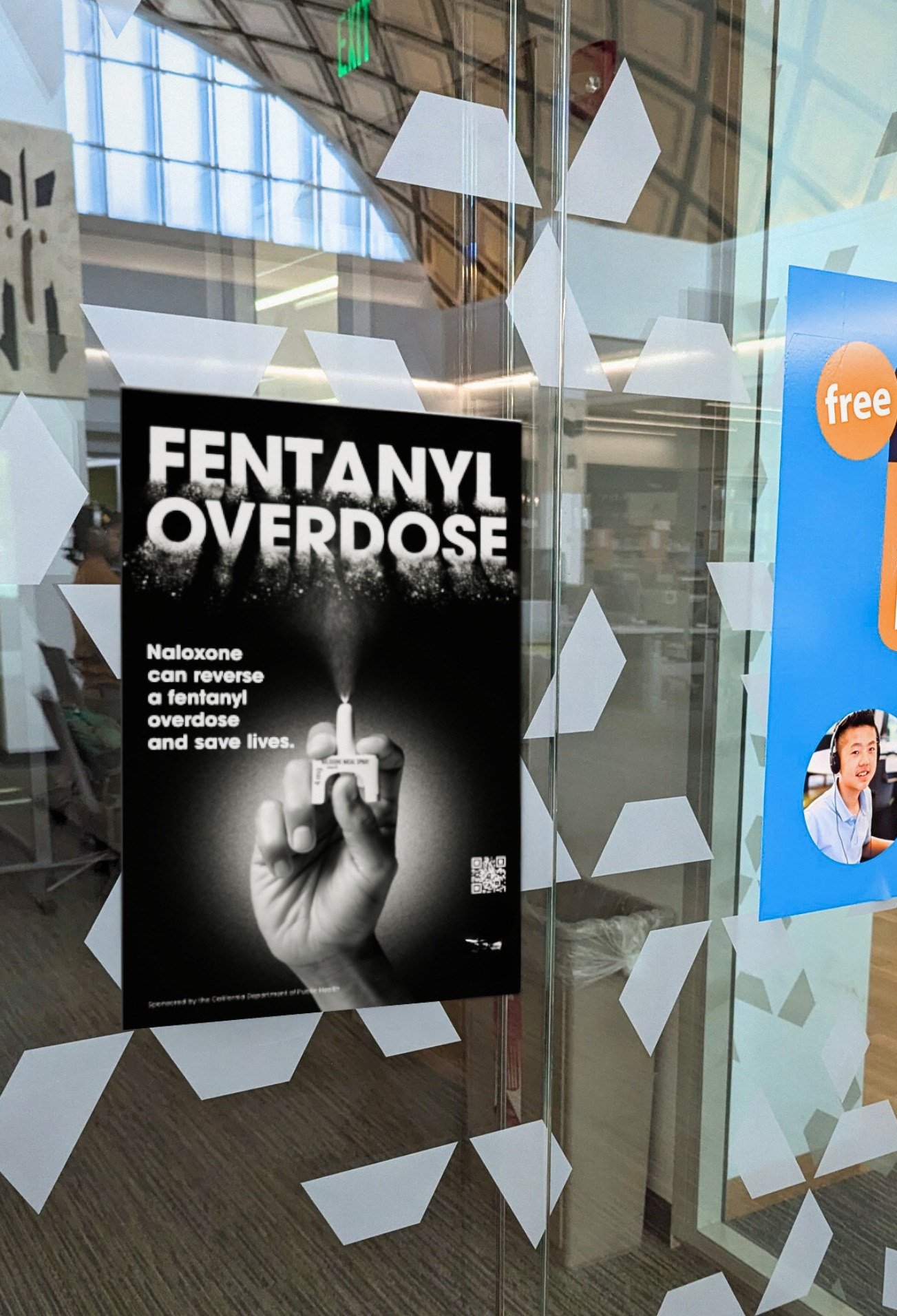 Naloxone awareness poster about fentanyl overdose on a glass door at a campus building
