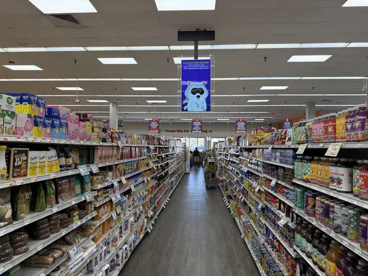 Grocery store aisle with a hanging ceiling sign above the shelves