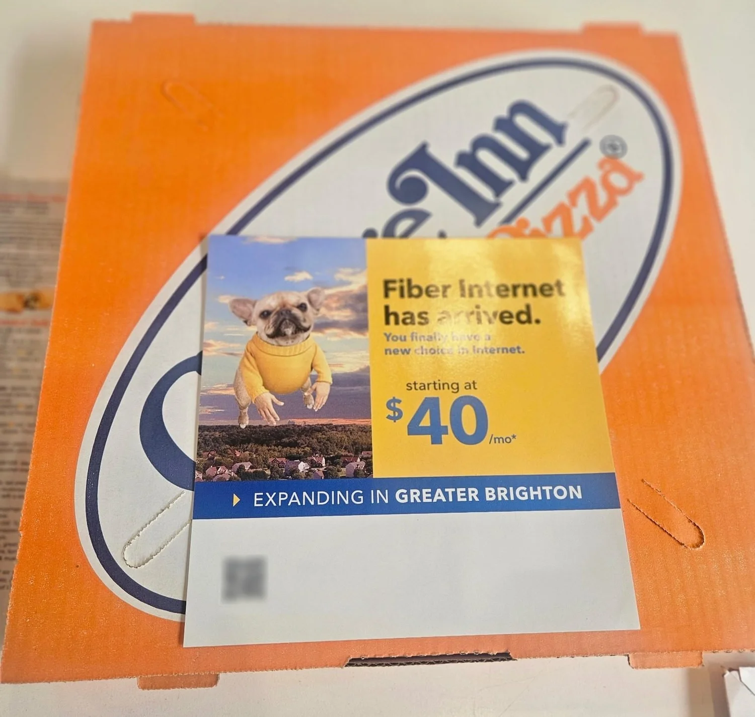 Pizza box topper card on top of an orange pizza box