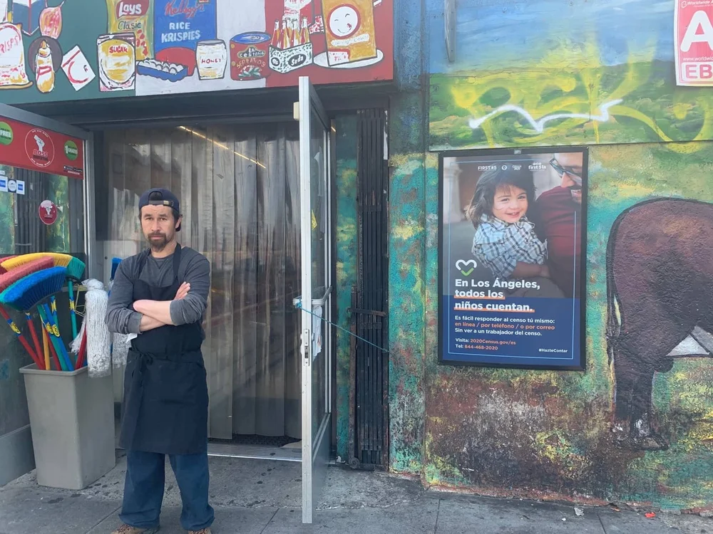 Shopper at a corner store entrance beside a health poster