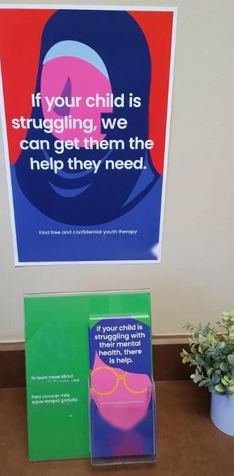 Youth mental health poster and bilingual take-one display at a front desk
