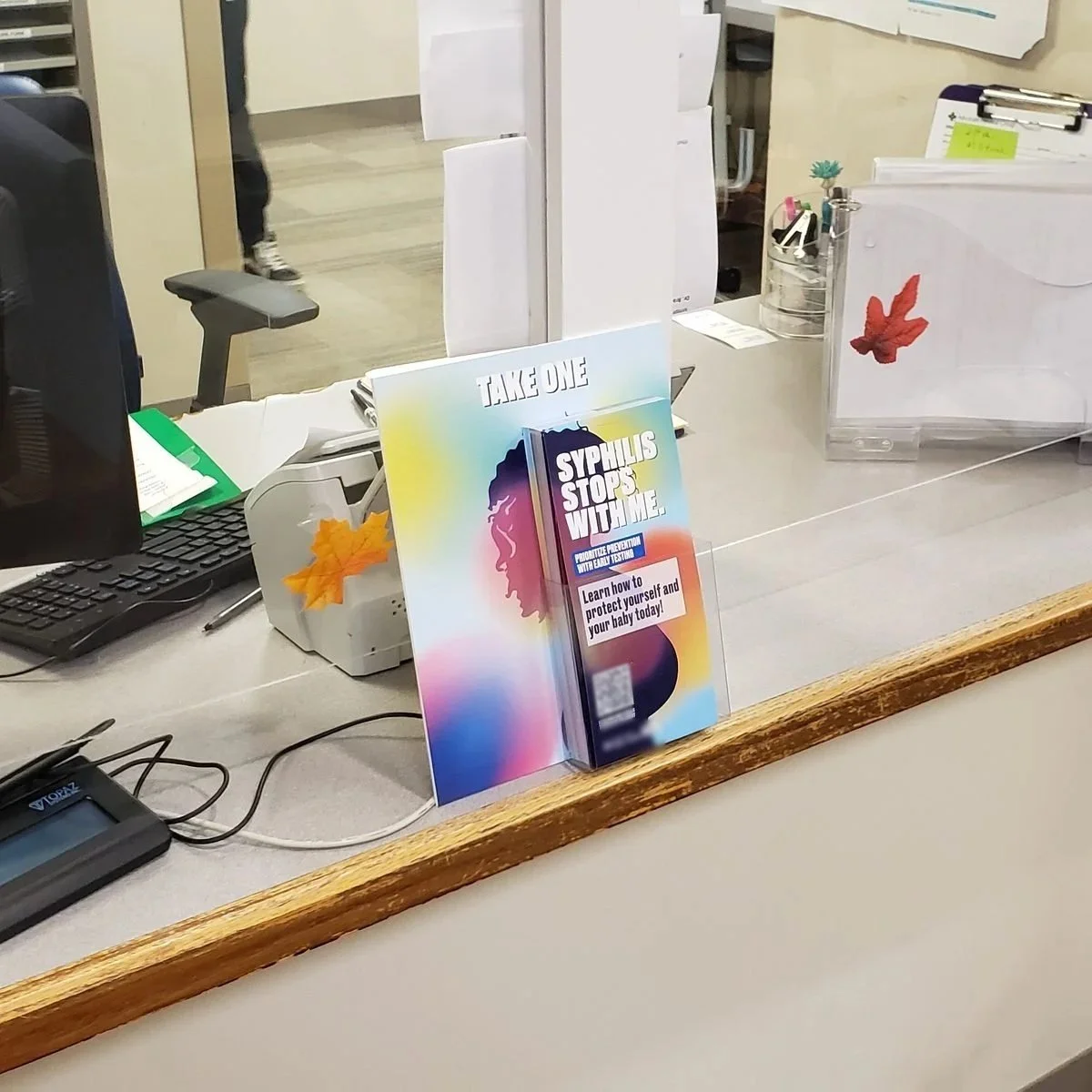 Take-one display of syphilis prevention cards, with a matching sign, on a clinic front-desk counter