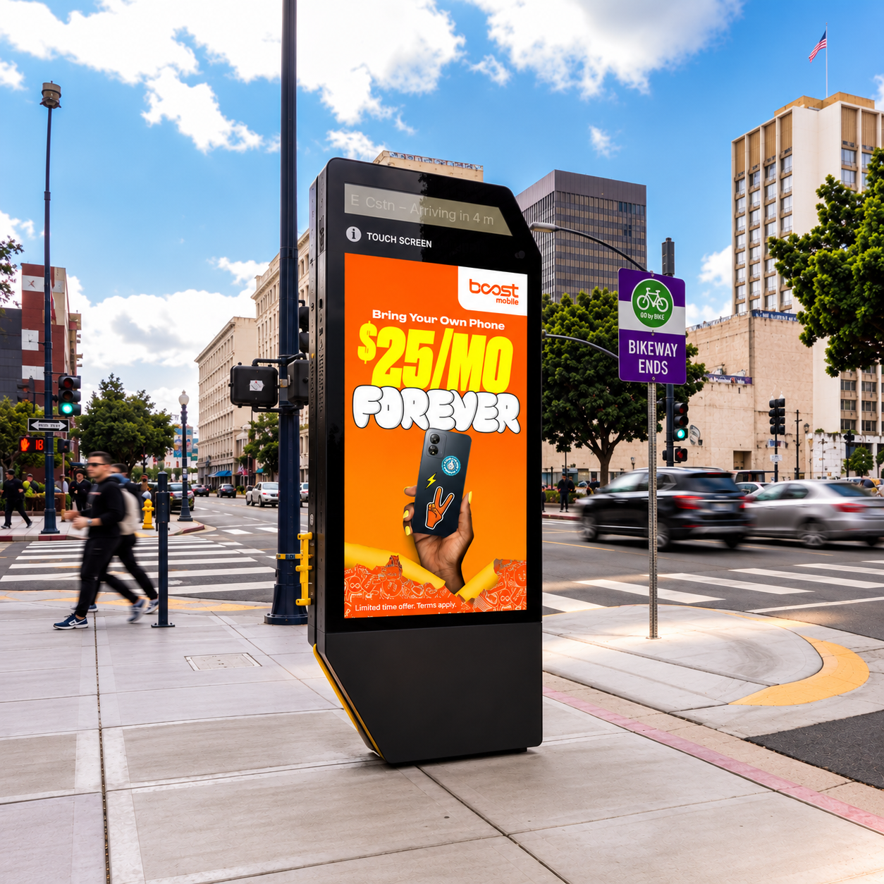 Boost Mobile ad on a digital sidewalk kiosk at a downtown crosswalk, with pedestrians crossing nearby