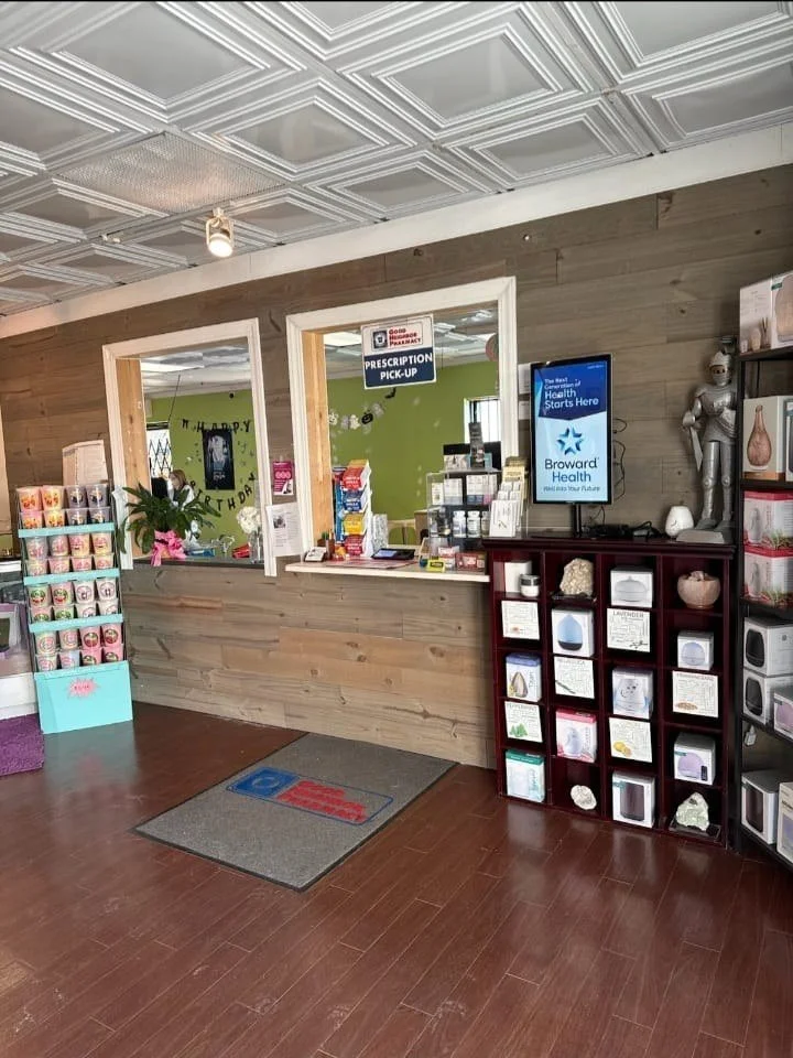 Digital screen with a health system ad beside the prescription pick-up window in a neighborhood pharmacy