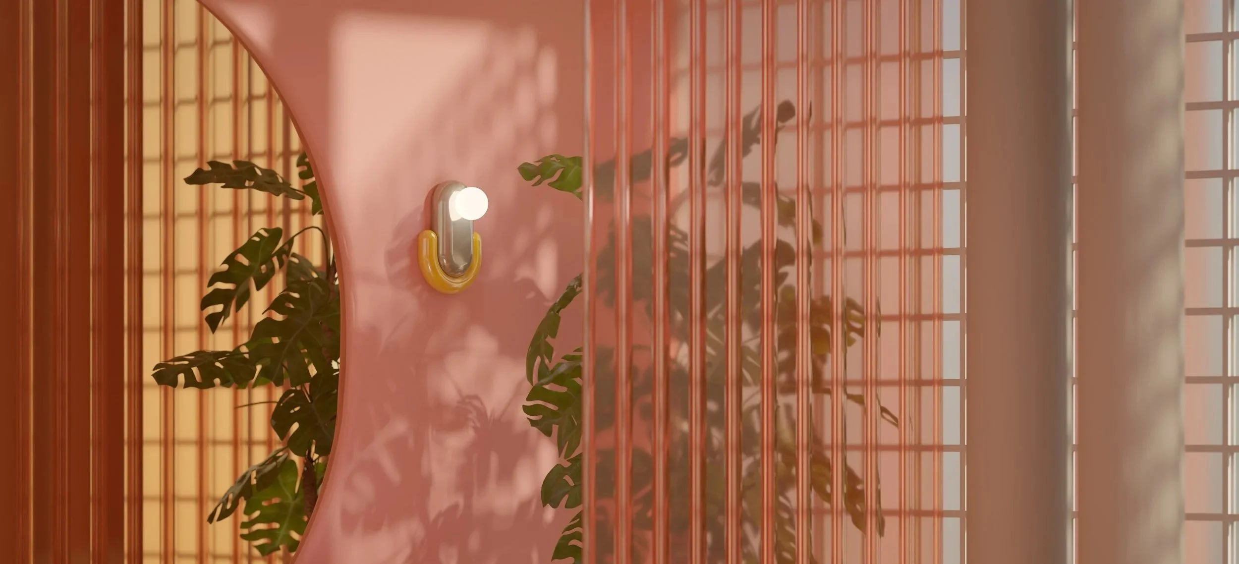 Pink wall area with a small yellow and silver light fixture attached to the wall, behind which are two potted plants with large, dark green leaves and a wooden slatted backdrop, and a lattice window in the background.