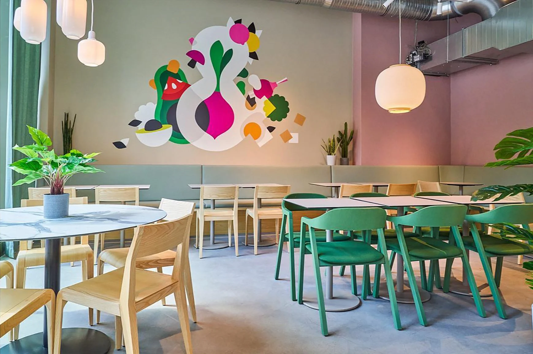 Interior of a modern cafe with tables and chairs, a colorful mural on the wall, potted plants, and soft lighting.