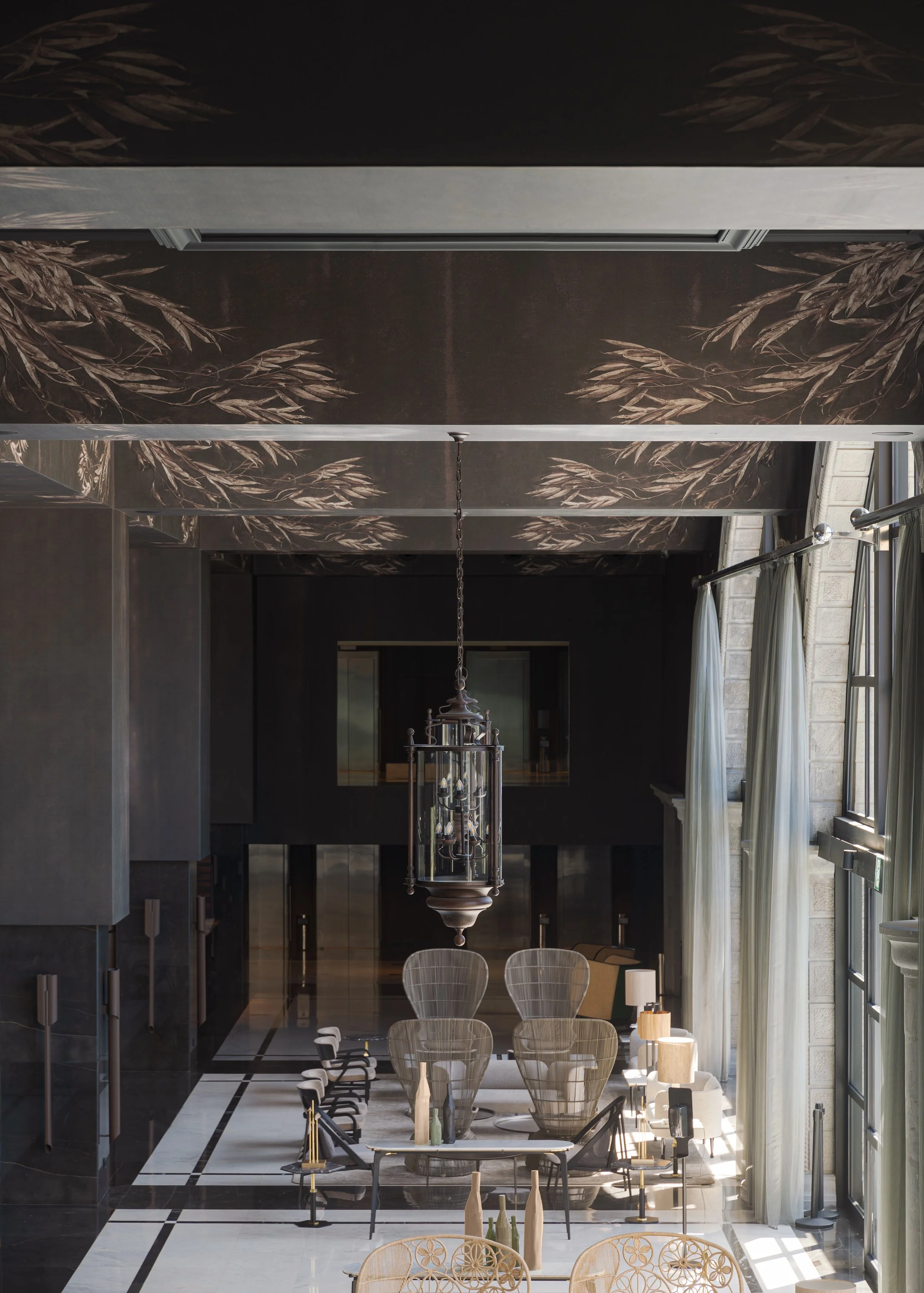 Hotel lobby with elegant furniture and wall mural on the ceiling with gold leaves and large windows