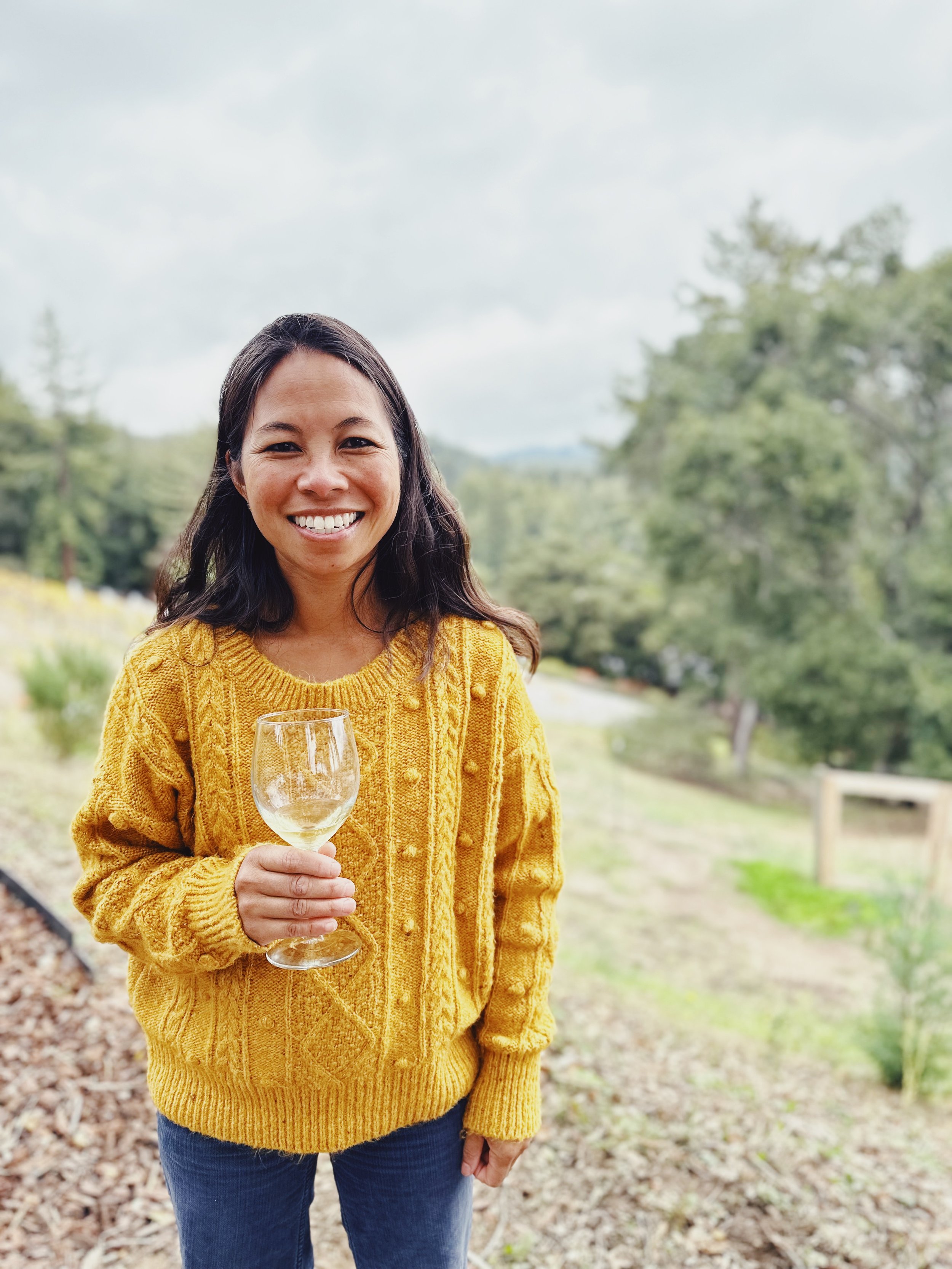 Woman in a yellow sweater enjoying a glass of Roberts Ranch wine
