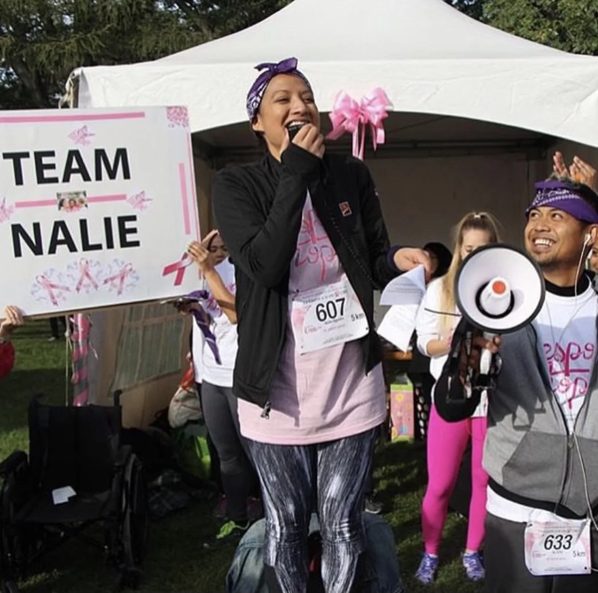 Nalie Agustin cheering beside a Team Nalie sign at a breast cancer walk