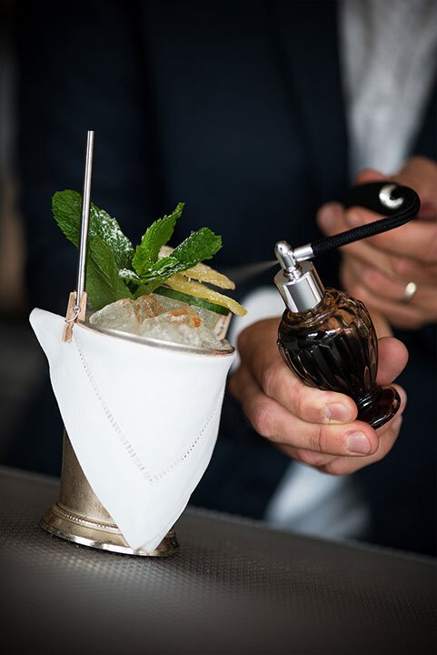  Close up of a bartender putting the finishing garnish on a frosty mint julep 