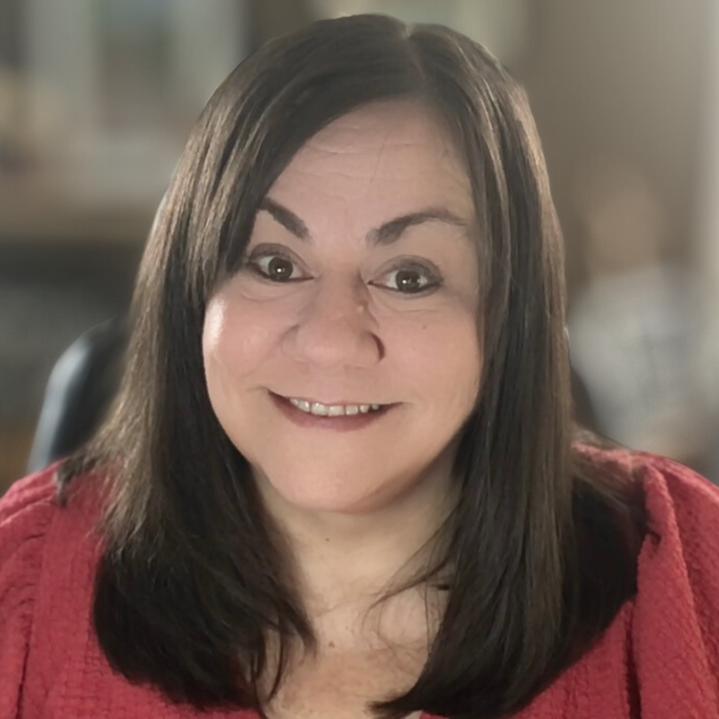 A woman with shoulder-length dark hair smiling at the camera, wearing a red sweater, in an indoor setting.