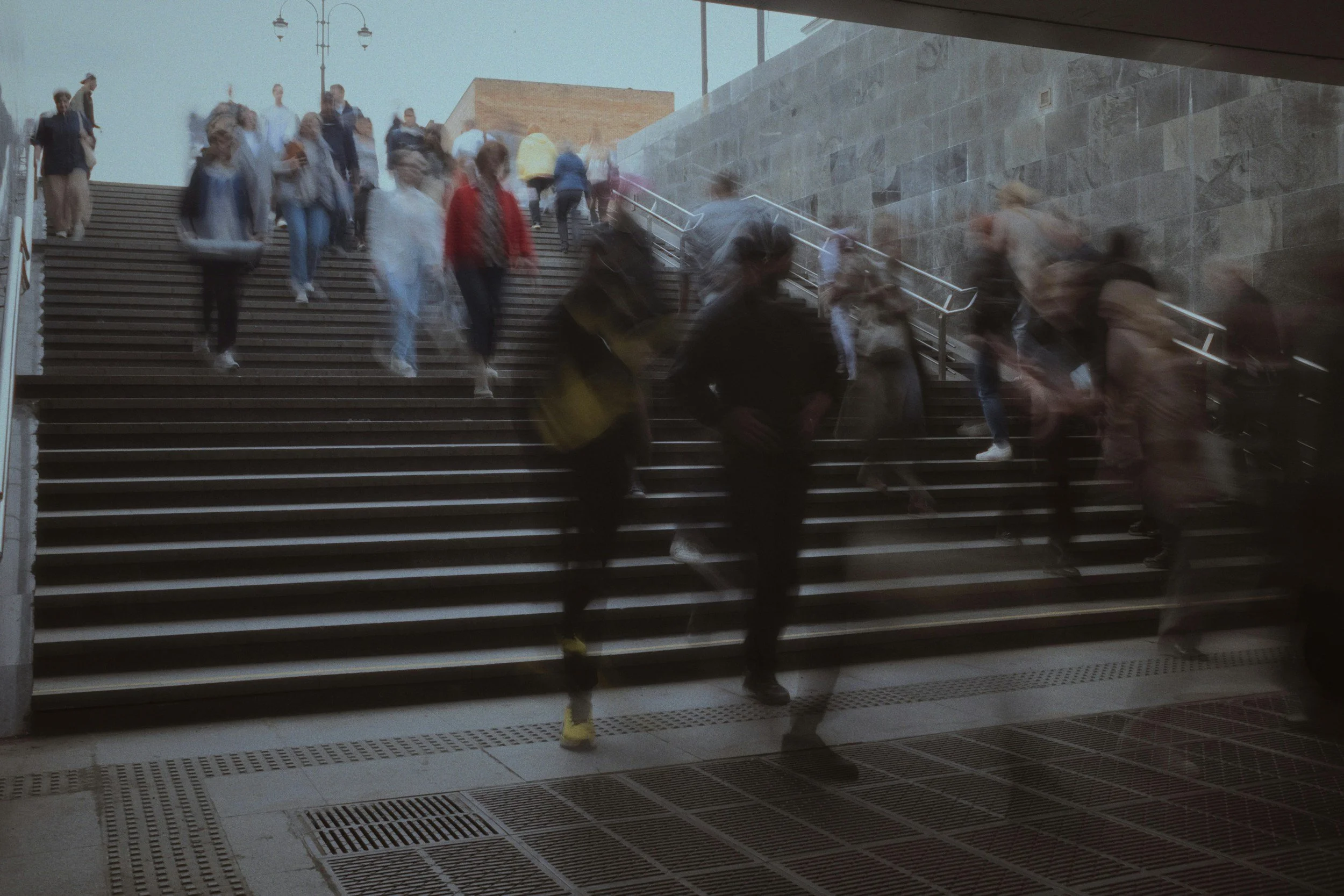 People walking up and down a staircase outside a building, some with blurred motion due to movement.