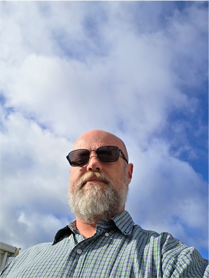 Mark McKenzie, NDIS Support Coordinator at ARK Planit, photographed outdoors under a blue sky.