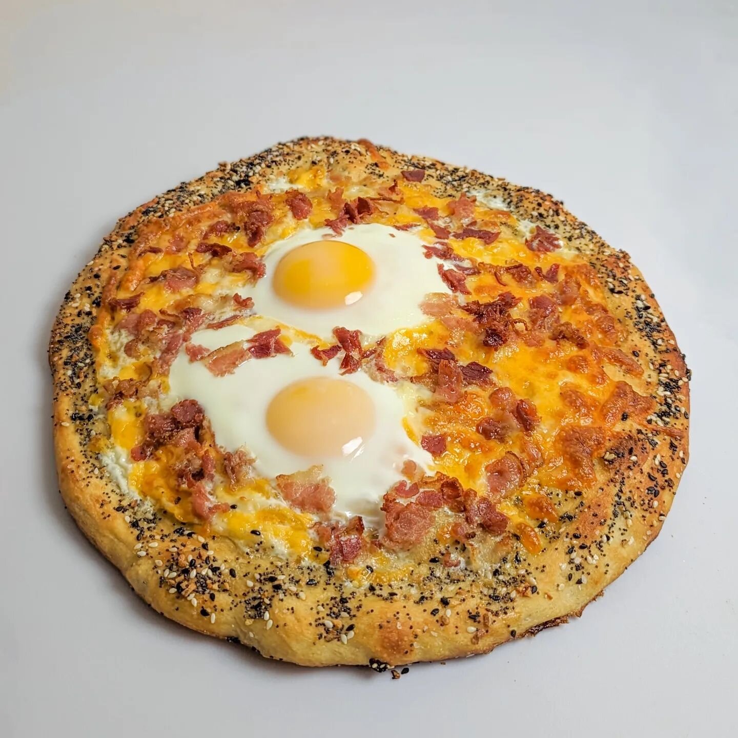 Breakfast pizza with cheese, bacon, and sunny side eggs 🍳🥓