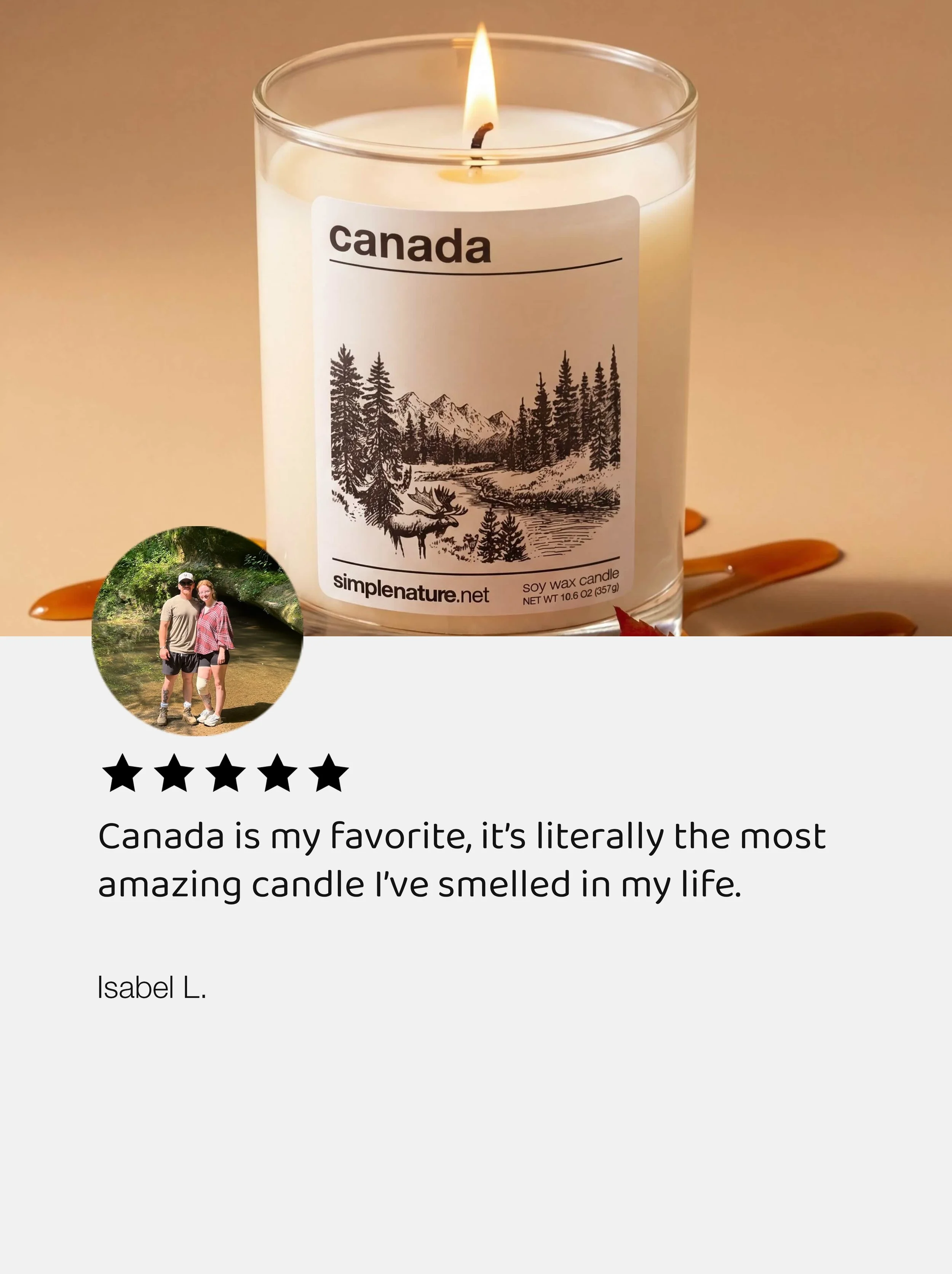 A white soy wax candle with a black and white otter landscape label, lit with a small flame, and orange and caramel-colored melted wax on a surface. Inset in bottom left corner is a small circular photo of a man and woman standing outdoors near a creek, smiling.