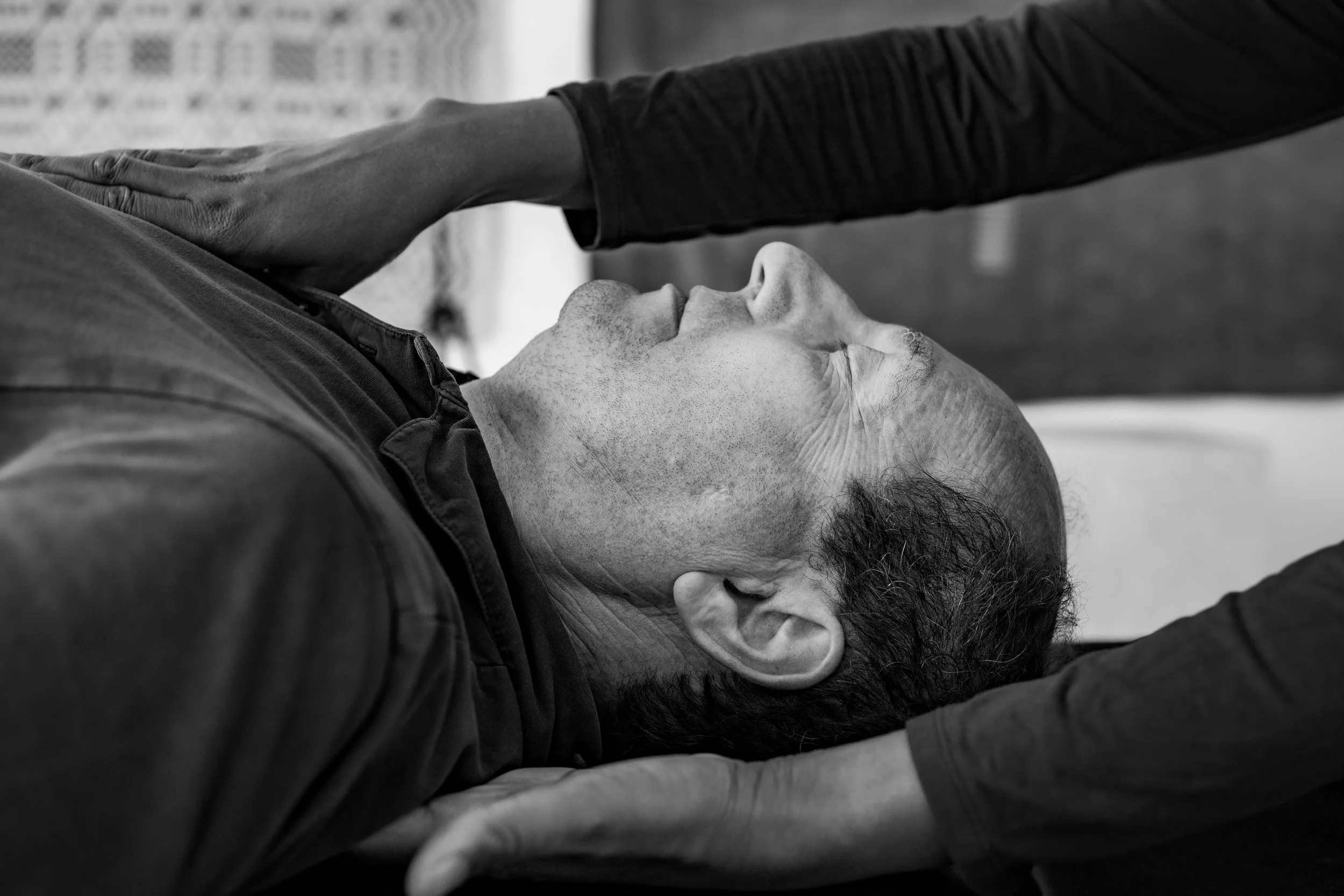 Black and white image of a person receiving one-to-one Feldenkrais session on neck and shoulders.
