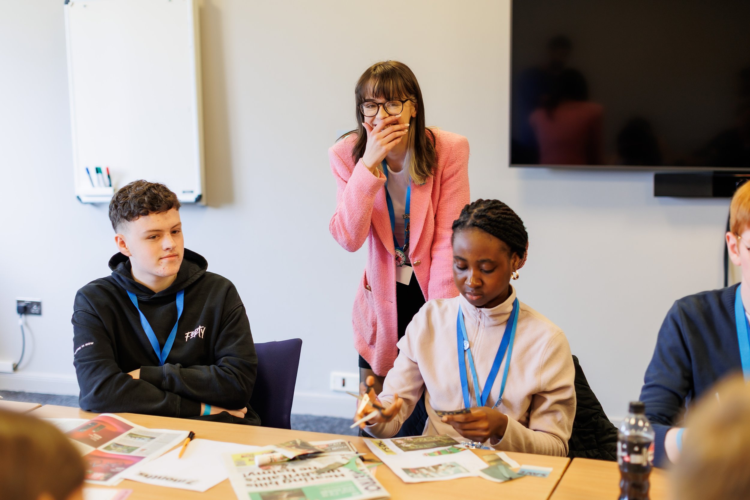 Members of the Scottish Youth Parliament interacting in a workshop. One of them is standing and laughing at the camera