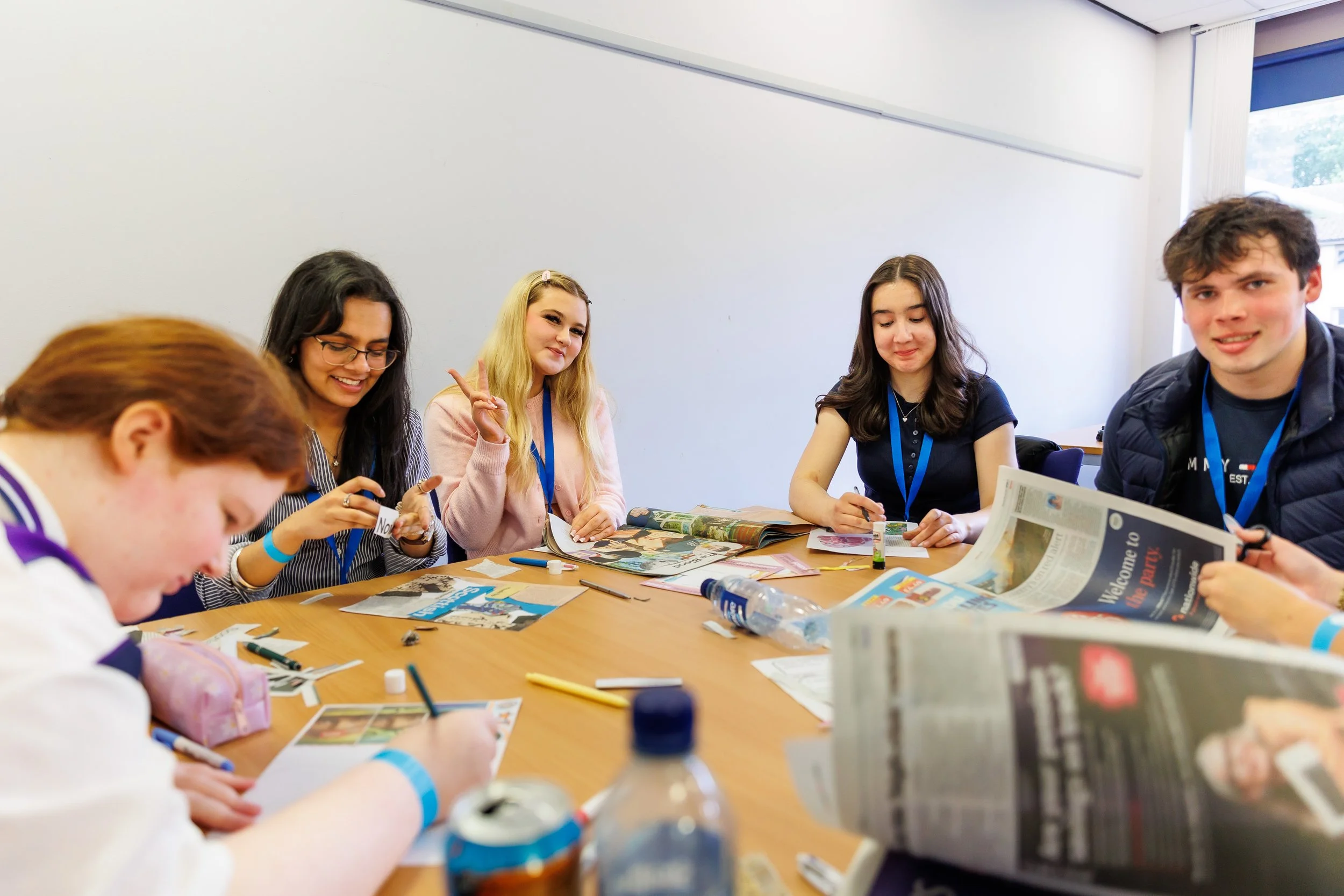 A group of five MSYPs sat around a table and doing craftwork. There are pieces of paper and pens on the table.