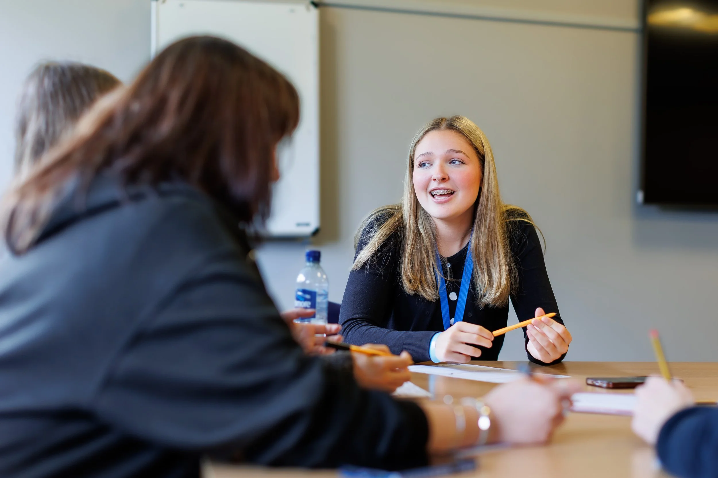 Three Members of the Scottish Youth Parliament chatting among themselves around at table with pens and pieces of paper.