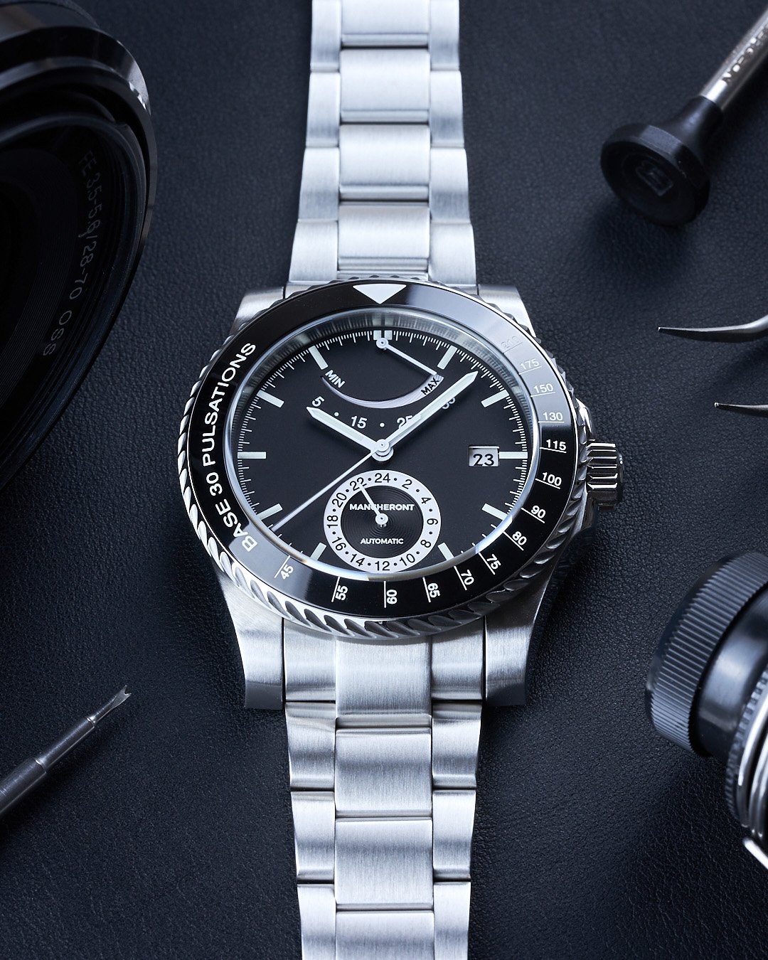 Front view of a black dial pulsometer men’s classy watch laid on black mat with accessories around