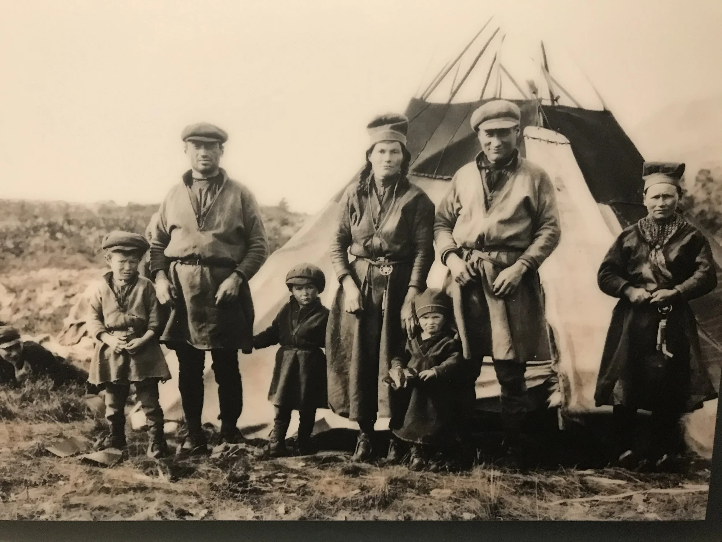 A black and white old photograph of a Sami family in front of their tent