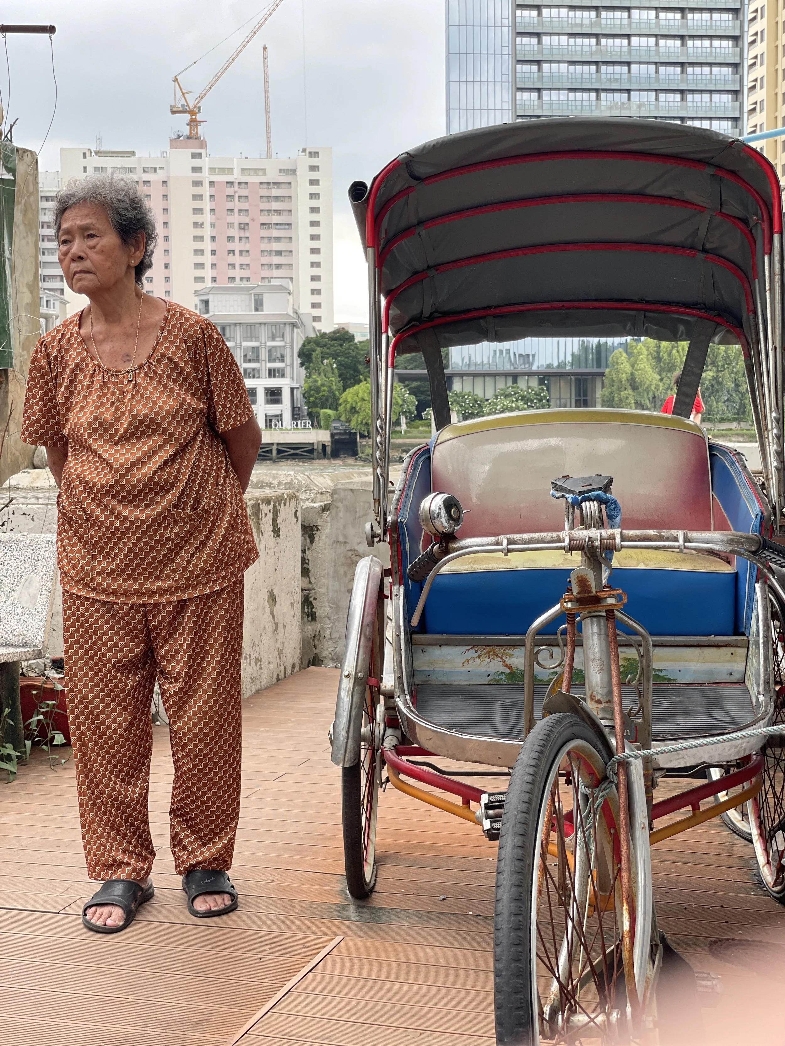 Thai Lady standing next to a TukTuk in Bangkok.