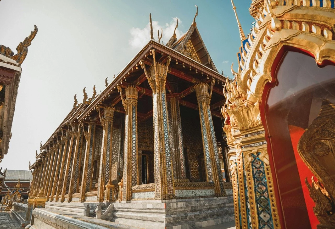 Thai temple with gold ornamentation and intricate architectural details under a clear sky.