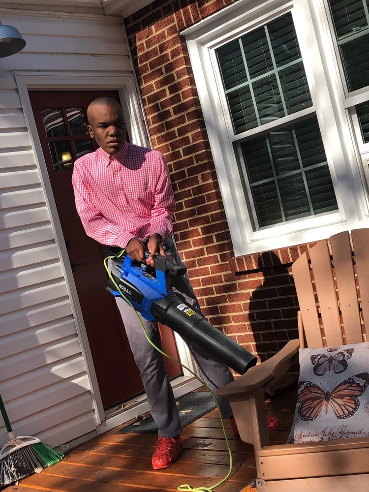 An apprentice leaf blowing, caring for the outdoor spaces