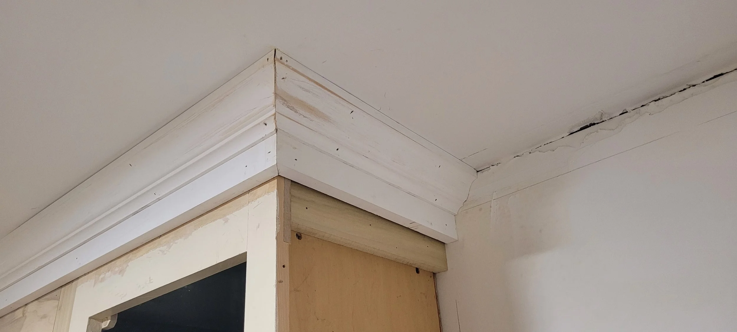  We had a contractor scrape the ceilings to remove all the popcorn texture from the ceiling. They didn’t mention that the ceiling at the corner of the kitchen was very uneven. When our carpenter installed the crown moulding in the kitchen, he discove