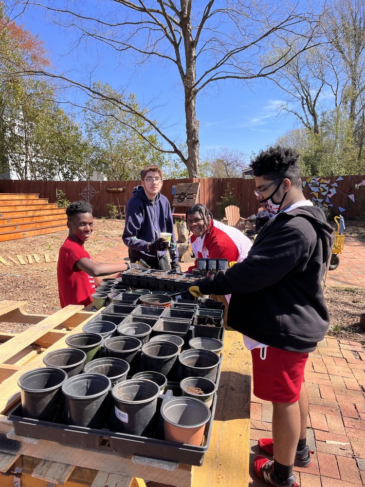 Apprentices planting seeds in pots made from upcycled magazine pages at Watsucker Urban Farm