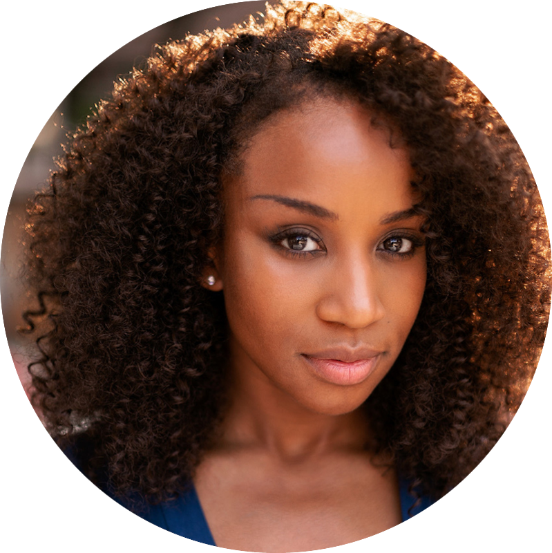 Close-up of a young African American woman with voluminous, curly hair and smooth skin, looking softly at the camera.