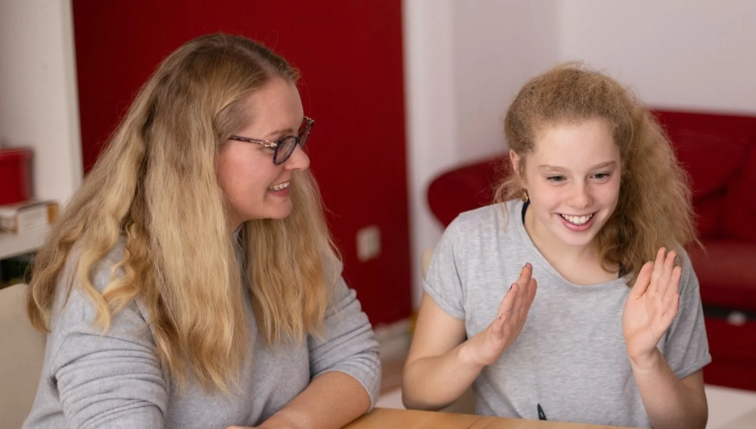 Two girls sitting at a table, smiling and laughing during a game or activity