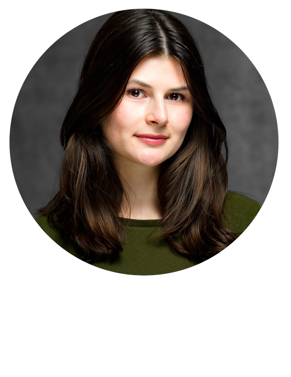 Portrait of a young woman with long dark brown hair, fair skin, and brown eyes, wearing a green top, against a gray background.