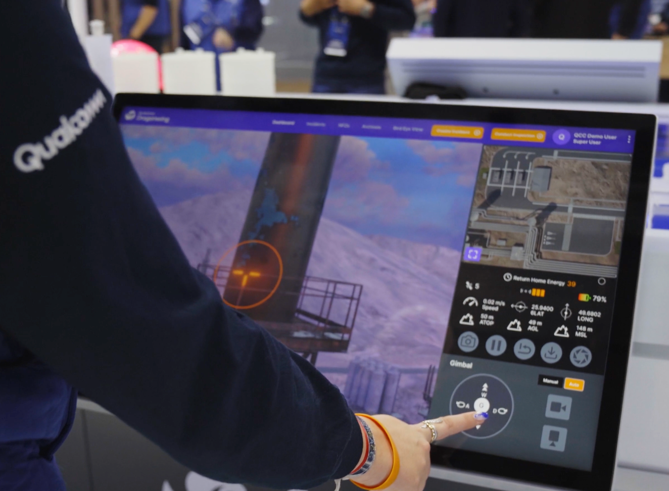Person using a drone control tablet displaying a 3D map and drone flight data at a trade show or exhibition.