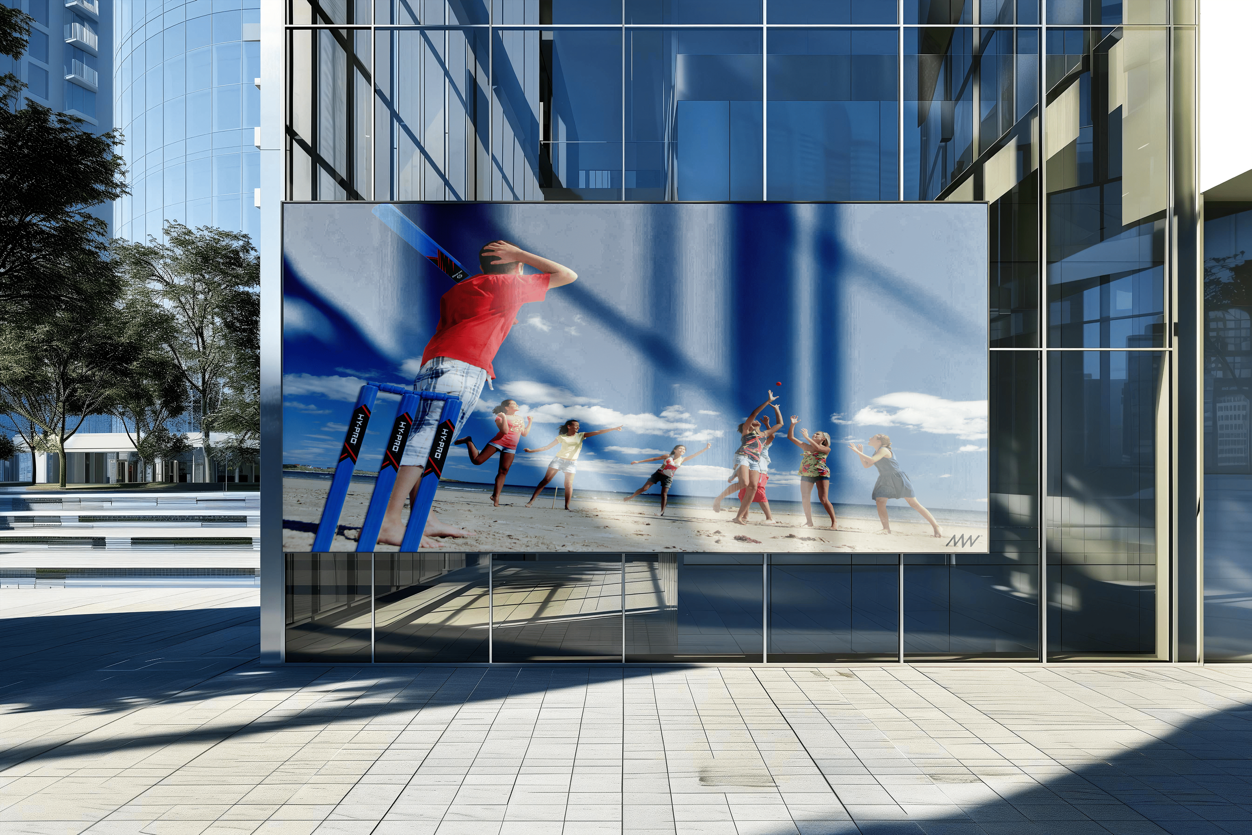 Outdoor billboard advertising beach cricket game with children playing, some jumping and some preparing to hit the ball, on a sandy beach under a blue sky.