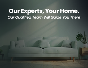 Living room with a white sofa, green plant, and wall with text: "Our Experts, Your Home. Our Qualified Team Will Guide You There."