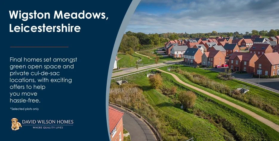 Aerial view of a residential neighborhood in Wigston Meadows, Leicestershire, showcasing red brick houses with red and dark gray roofs, green open spaces, walking paths, and surrounding greenery under a partly cloudy sky.