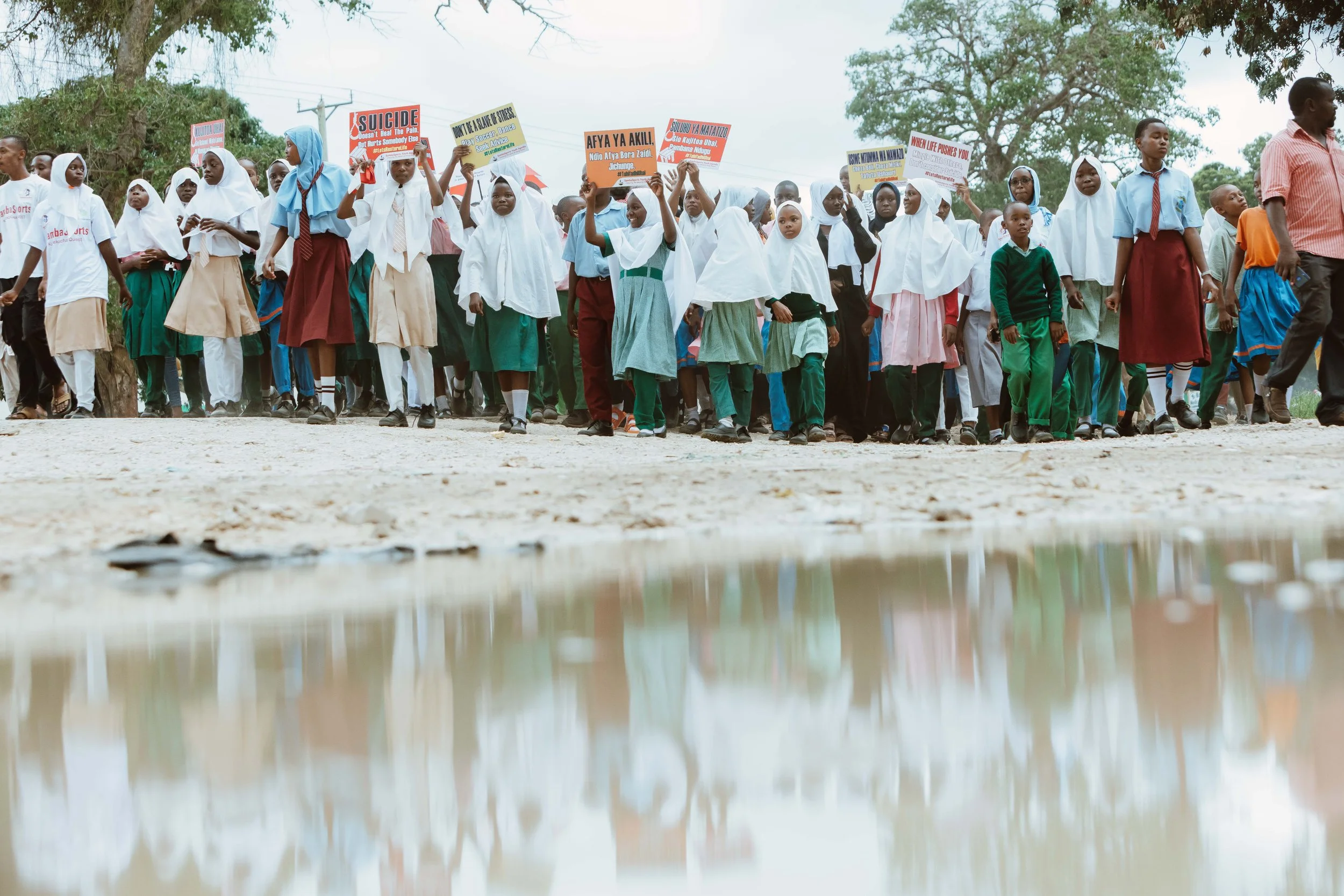 A pensive African man sits on a bench inside a dilapidated concrete building.