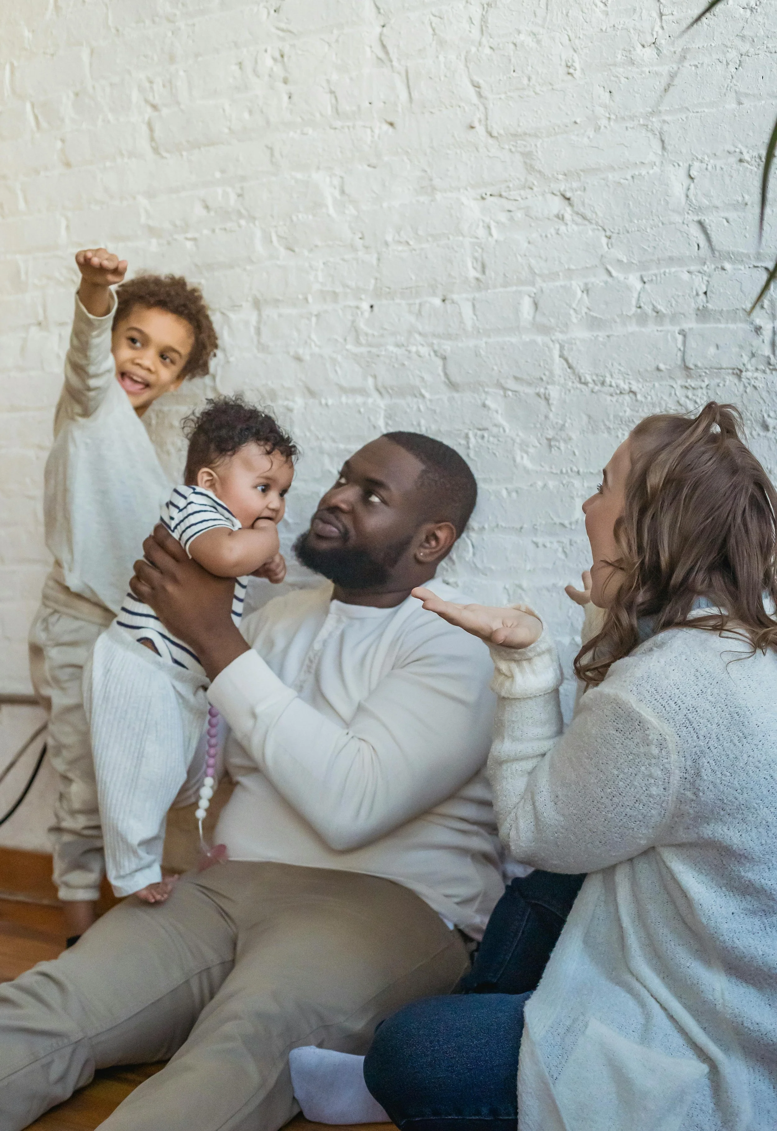 A parent holding a baby while engaging with a toddler during a playful interaction that highlights parenting support in Oakland.