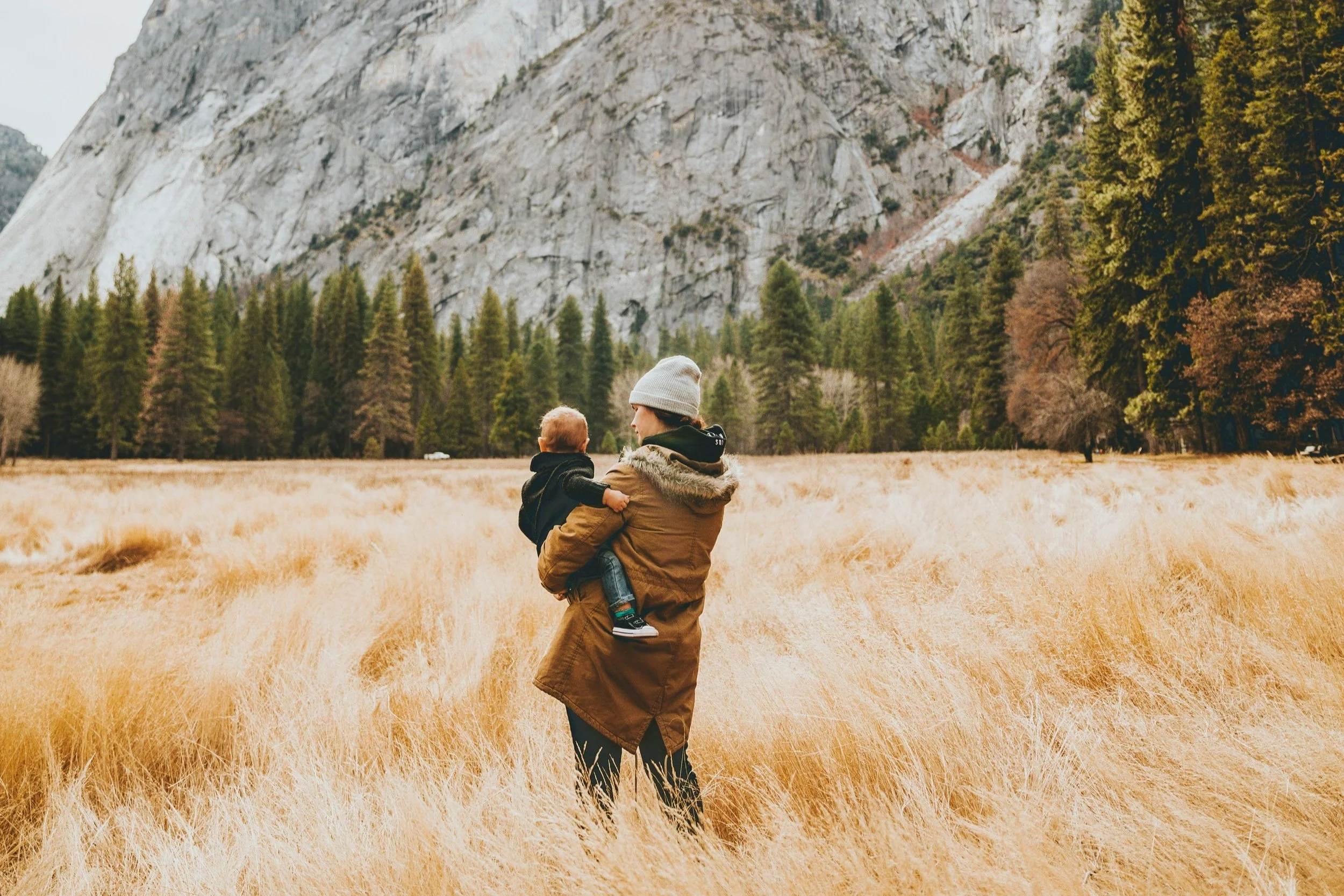 A parent holding their child while standing in an open meadow, symbolizing parent child relationship support in the Bay Area.