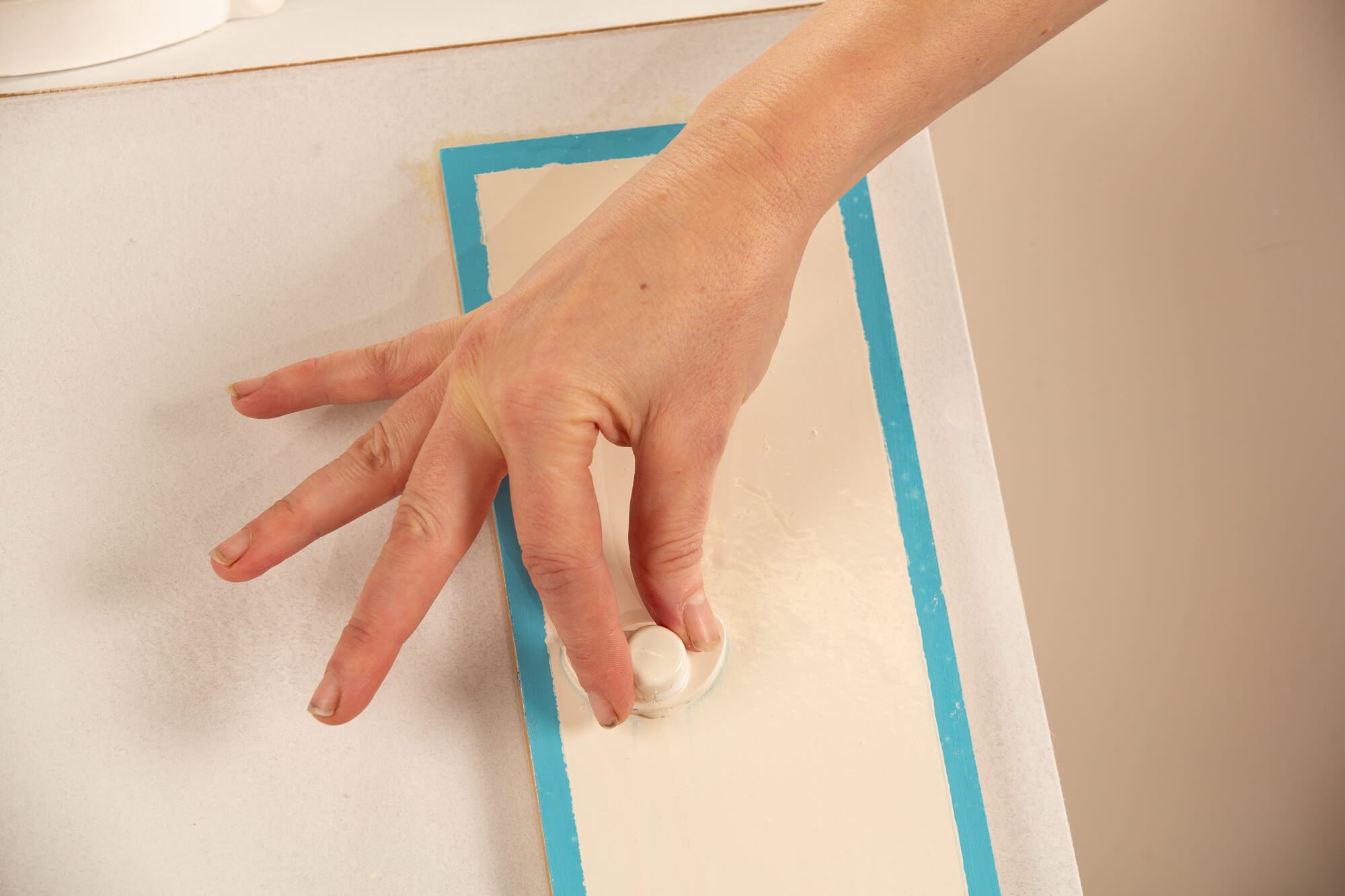 A person's hand is pressing a white rubber stamp on a white sheet of paper that has a blue border.
