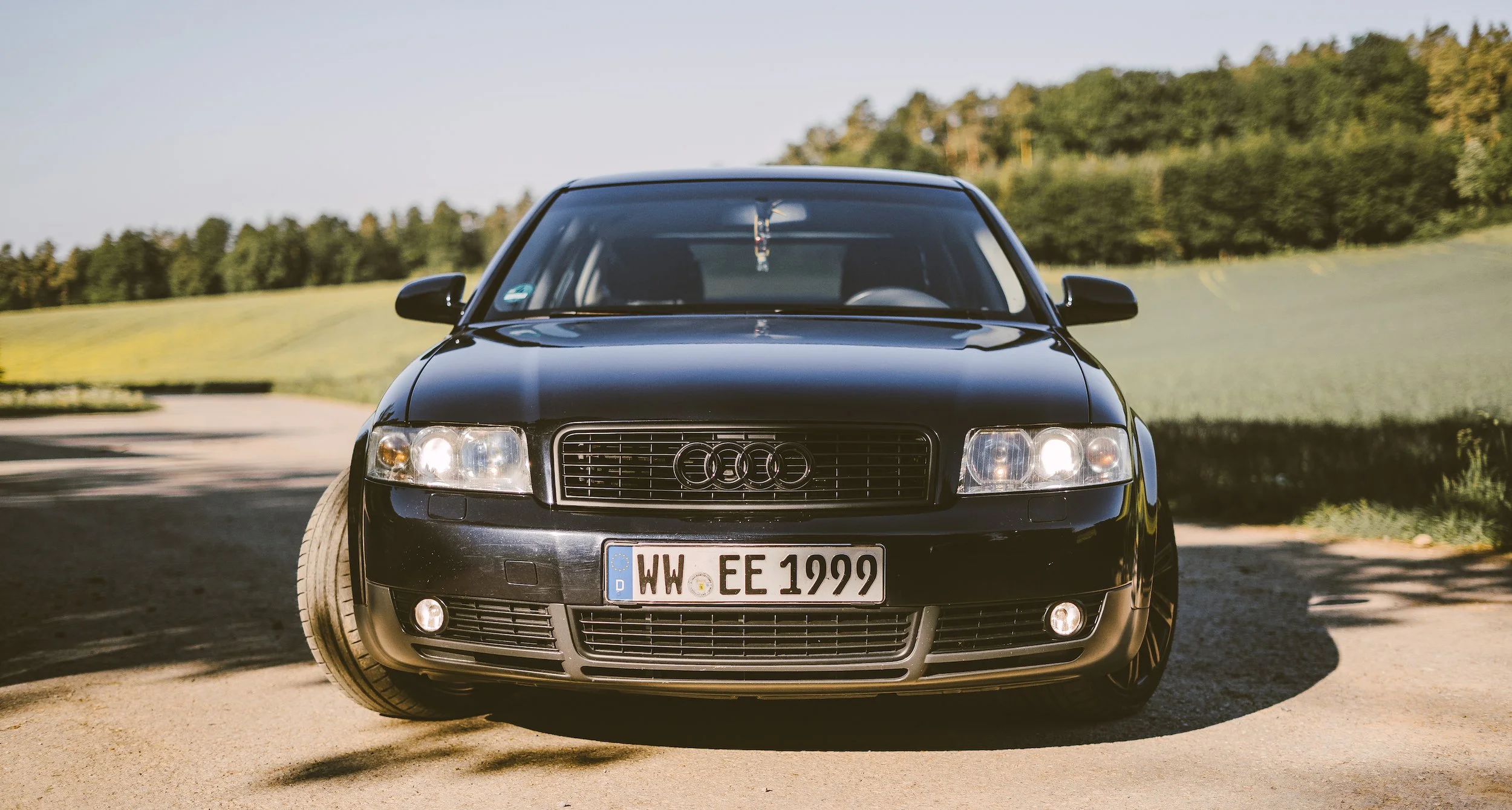 Schwarzer Audi A3 auf Landstraße mit grünem Acker im Hintergrund