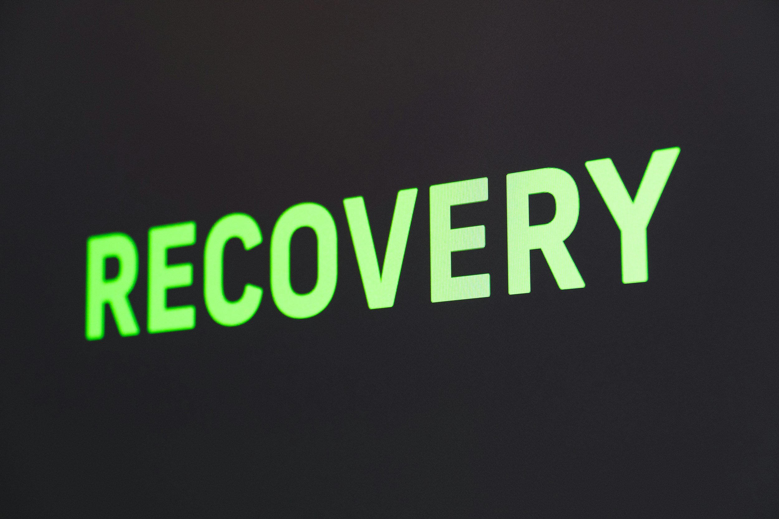 Close-up of a digital screen displaying the word 'RECOVERY' in bright green text.
