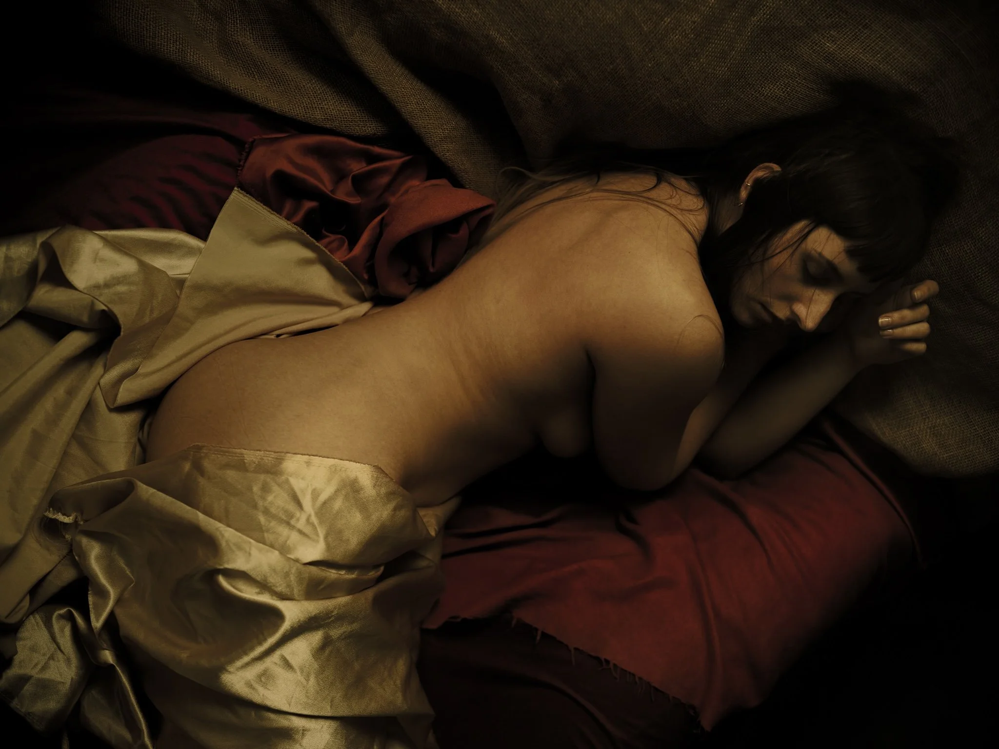 A woman laying on a bed. This image resembles renaissance painting.